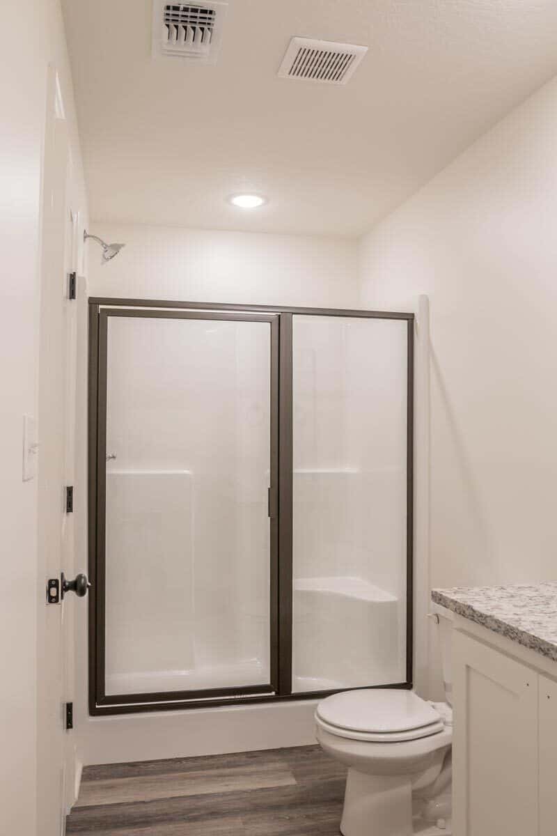 另一间浴室有一个洗手池梳妆台、一个马桶和一个带滑动玻璃门的步入式淋浴间。