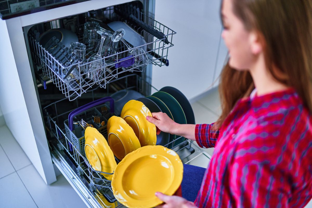 女人从洗碗机里拿盘子。