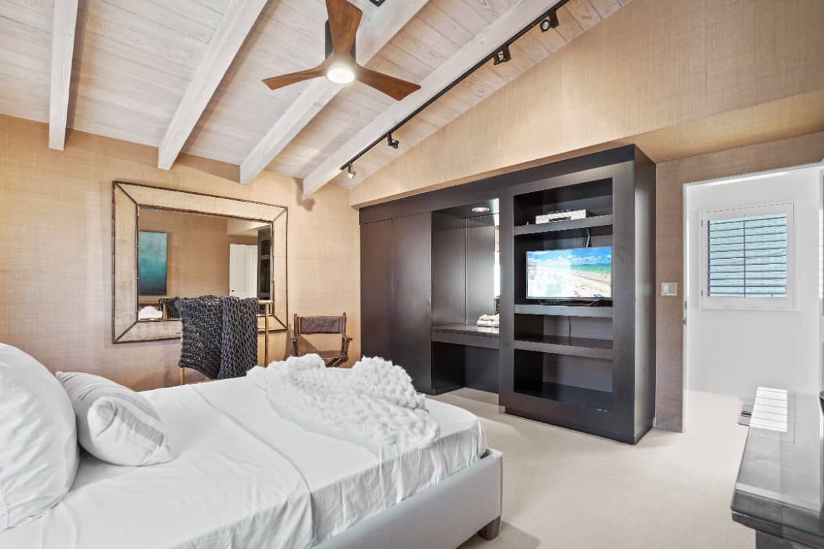 这间卧室设有拱形木梁天花板和一个带梳妆台和电视架的内置橱柜。图片来自Toptenrealestatedeals.com。
