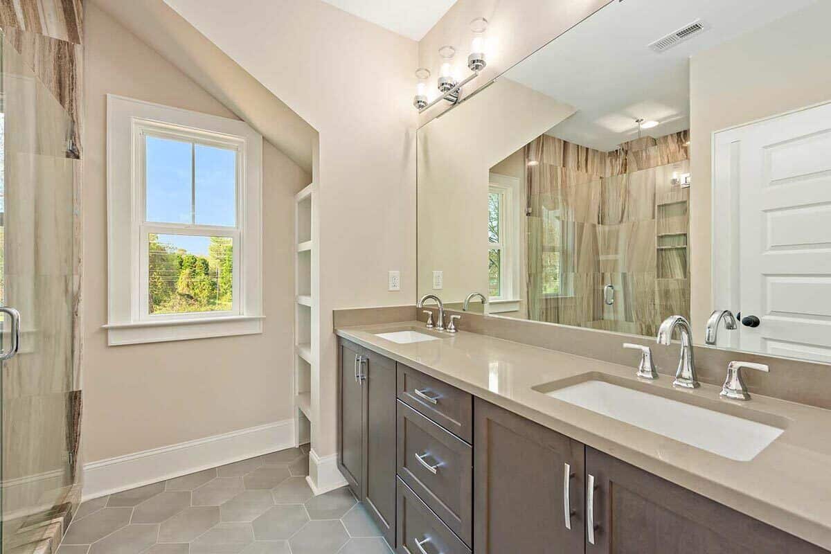 主浴室带有步入式淋浴间和一个配有双水槽和无框镜子的大梳妆台。