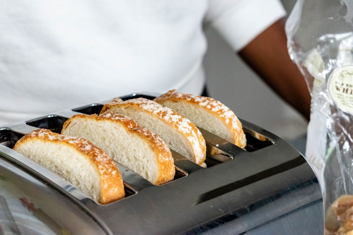 一个女人把面包放在烤面包机上。