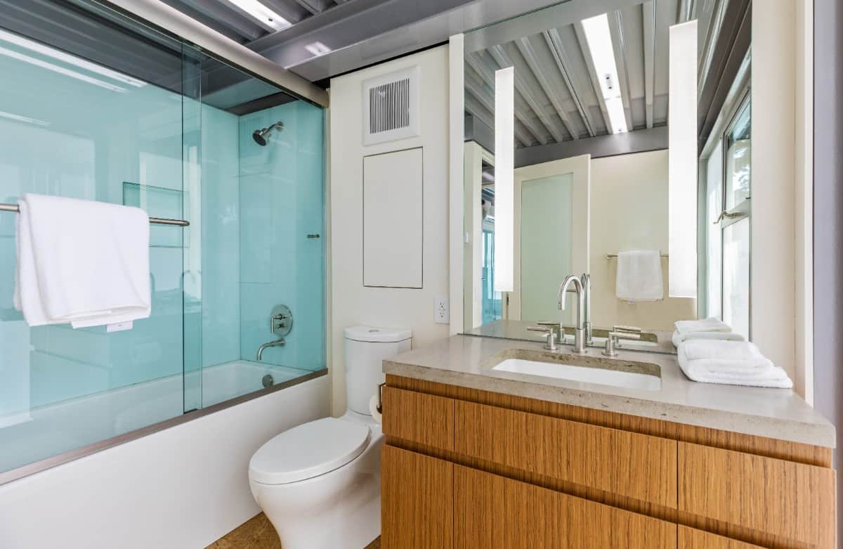 这个浴室提供了一个洗手台，一个厕所，一个浴缸和淋浴组合，封闭在滑动玻璃门里。图片来自Toptenrealestatedeals.com。
