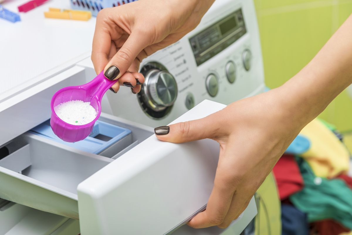 一名妇女将洗衣粉倒在洗衣机上。