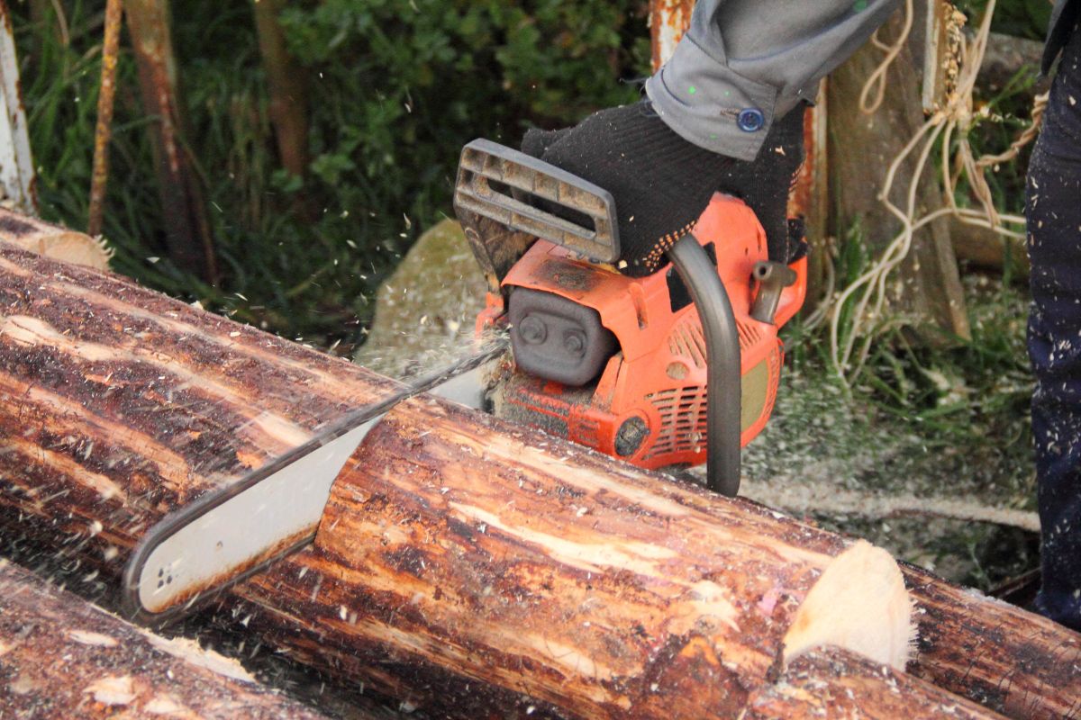 一个人试图用链锯锯木头。
