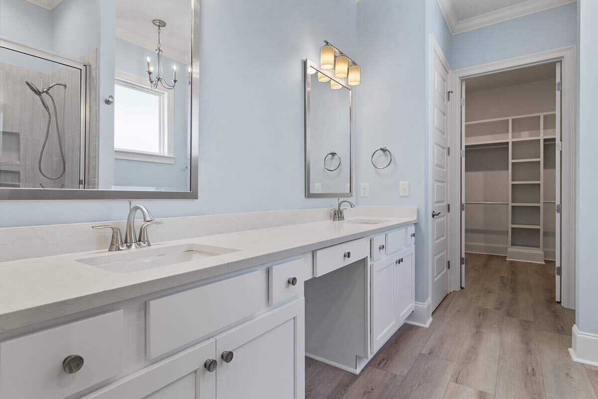 主浴室设有双洗手池梳妆台和一间步入式淋浴间，在镀铬镜框的镜子中映出淋浴间的倒影。