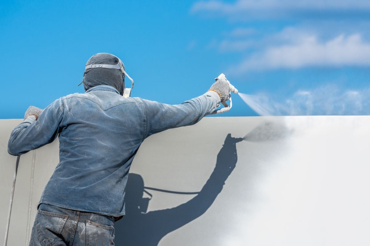 一个油漆工正在建筑物顶部喷漆。