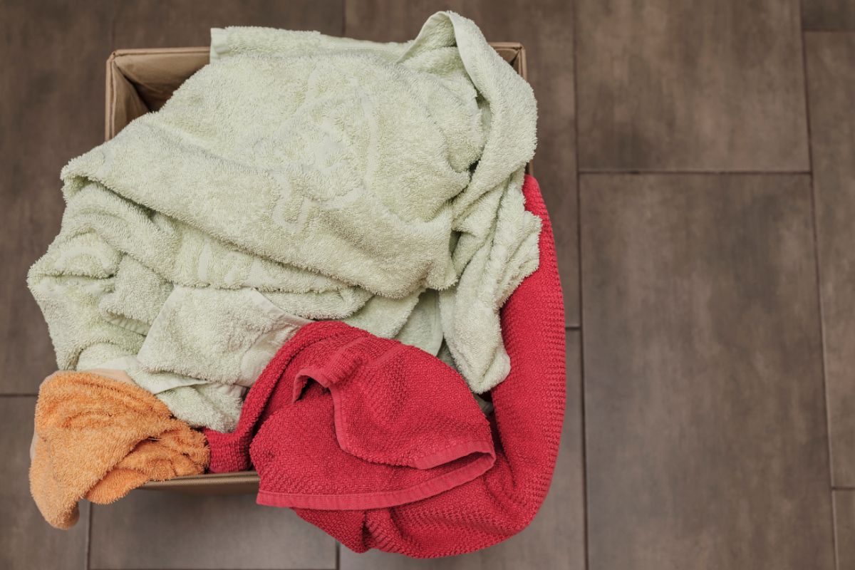 颜色鲜艳的毛巾放在一个盒子里洗，黑色瓷砖背景上有一堆脏衣服。