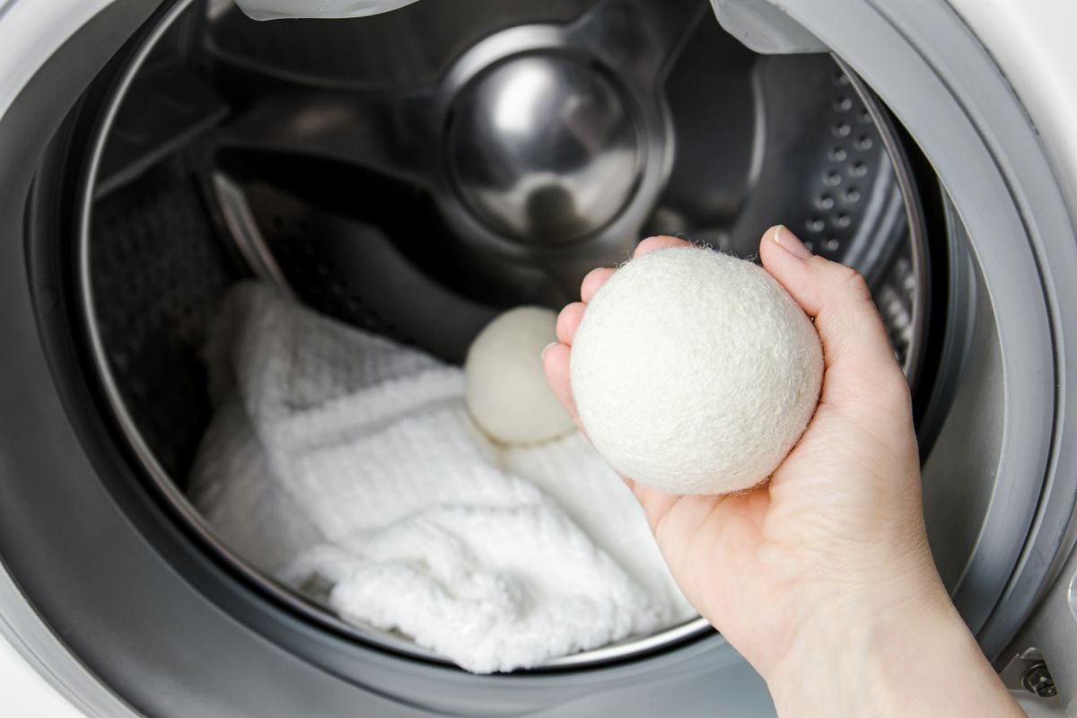一个女人使用羊毛烘干机球的概念更软的衣服，而在洗衣机滚筒干燥。