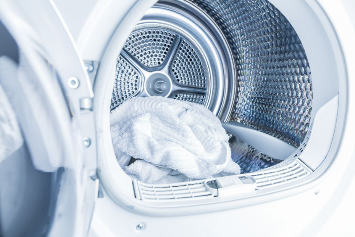在一个装满一尘不染的白色毛巾的滚筒式烘干机里，是一个现代家庭概念的烘干机。