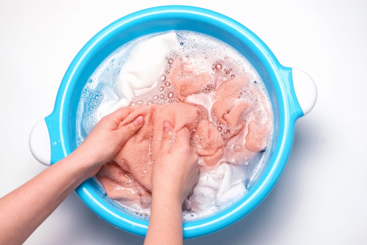 俯视图的女性手洗各种颜色的毛巾在水槽。
