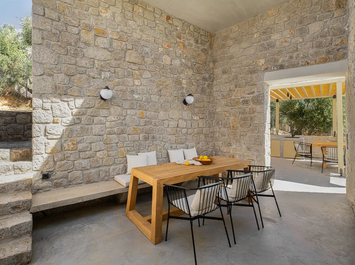 户外餐厅,石砖墙,木制的餐桌和金条类型椅子。