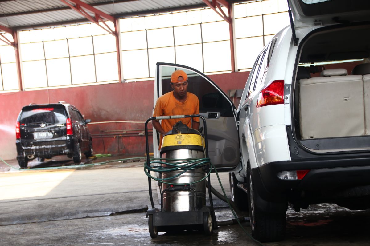 一个男人正在用高压清洗机清洗汽车。