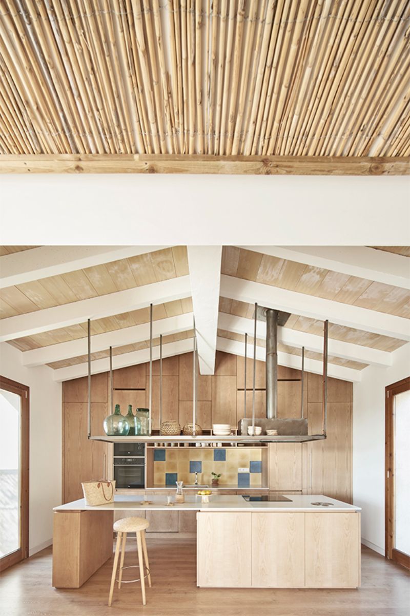 厨房里有低成本的横梁天花板、深褐色木材、手工水泥地板和水槽。