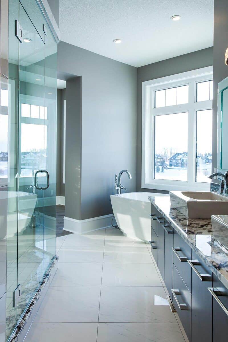 主浴室带步入式淋浴，一个独立的浴缸，和一个配有两个容器水槽，铬固定装置和花岗岩台面的梳妆台。