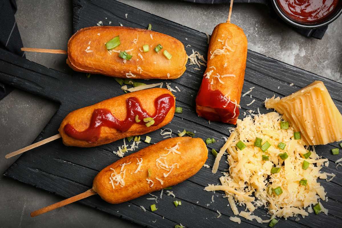玉米热狗和辣番茄酱通心粉和奶酪在木板上。