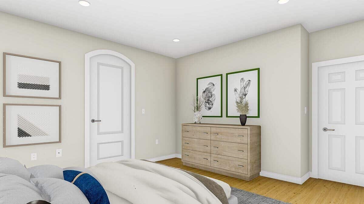 主卧室有一张舒适的床，一个木制梳妆台，和白色墙壁上的框架艺术品。