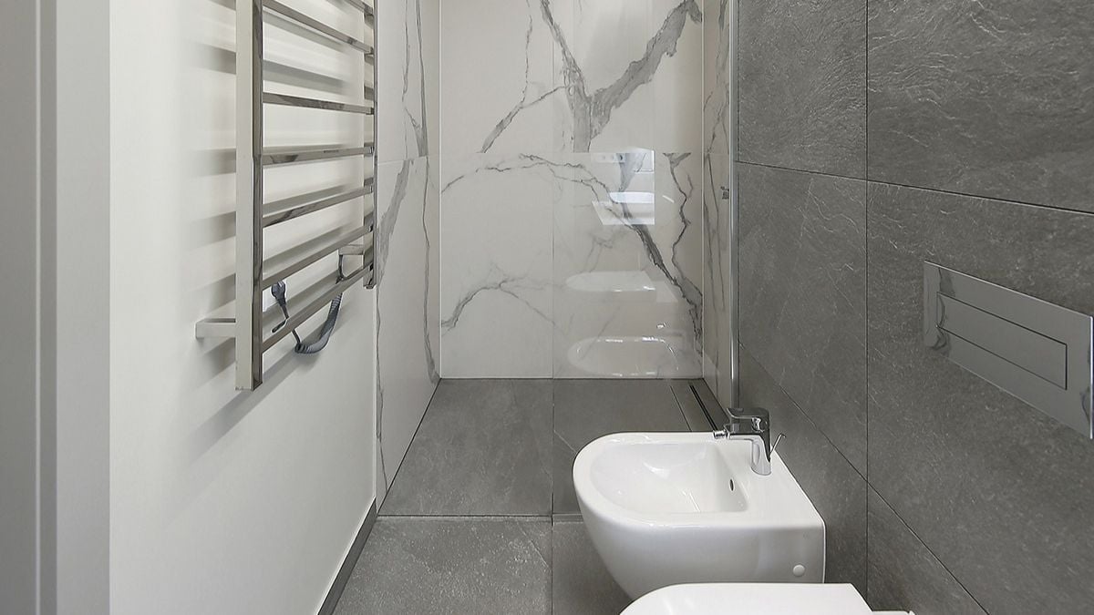 浴室石材纹理的灰色浮雕设计与房间的白色大理石瓷砖形成对比。