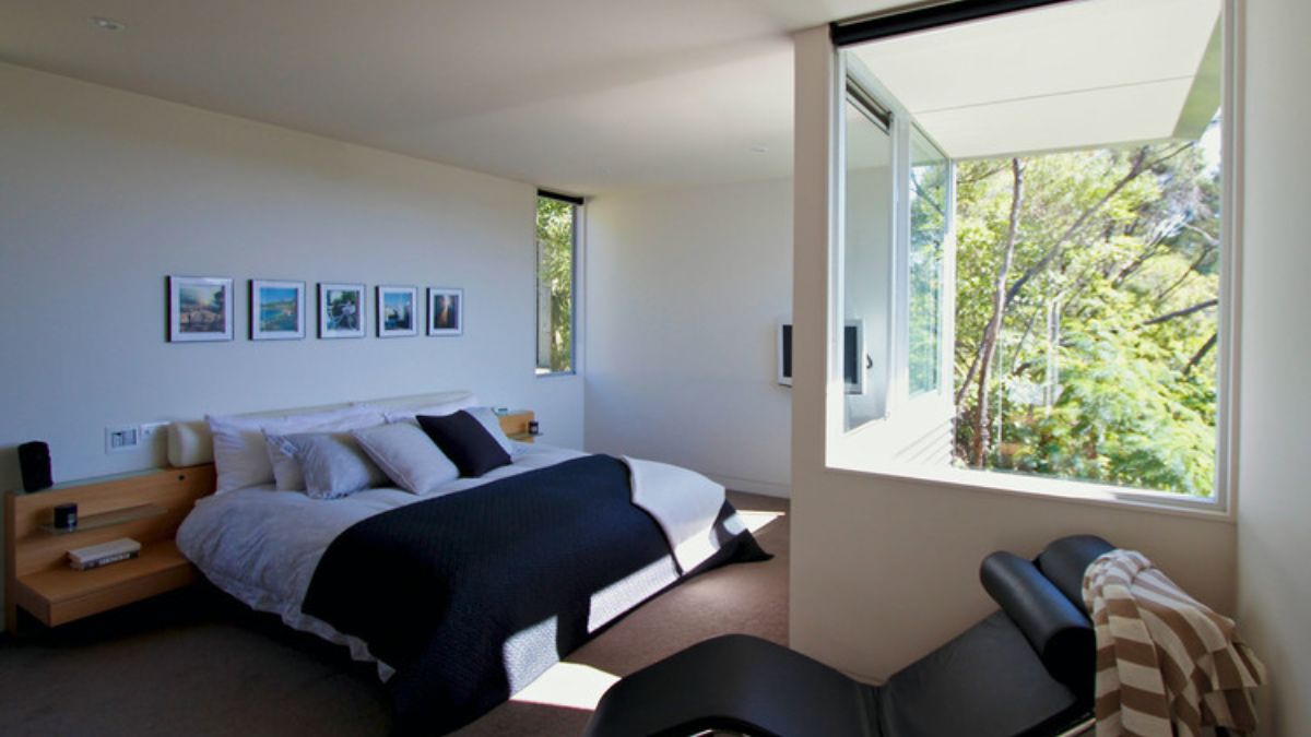 简约的室内拍摄但宽敞的卧室,和大量的自然光线流在通过大玻璃窗,创造一个宁静和诱人的氛围。