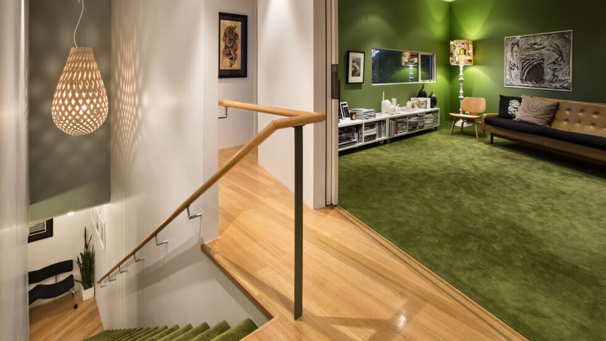 室内照片从楼梯的顶端,展示一个开放的房间,一个绿色的配色方案框架的右侧可见。