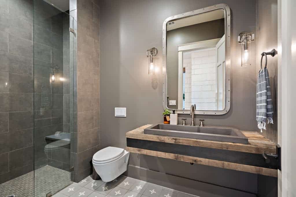 这间浴室有一个水槽、一个壁挂式厕所和一个带瓷砖长凳的步入式淋浴间。