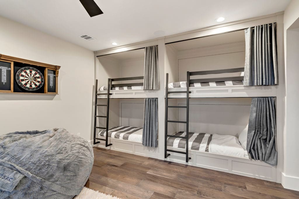 这间卧室设有定制的双层床，配有锻铁梯子和栏杆。