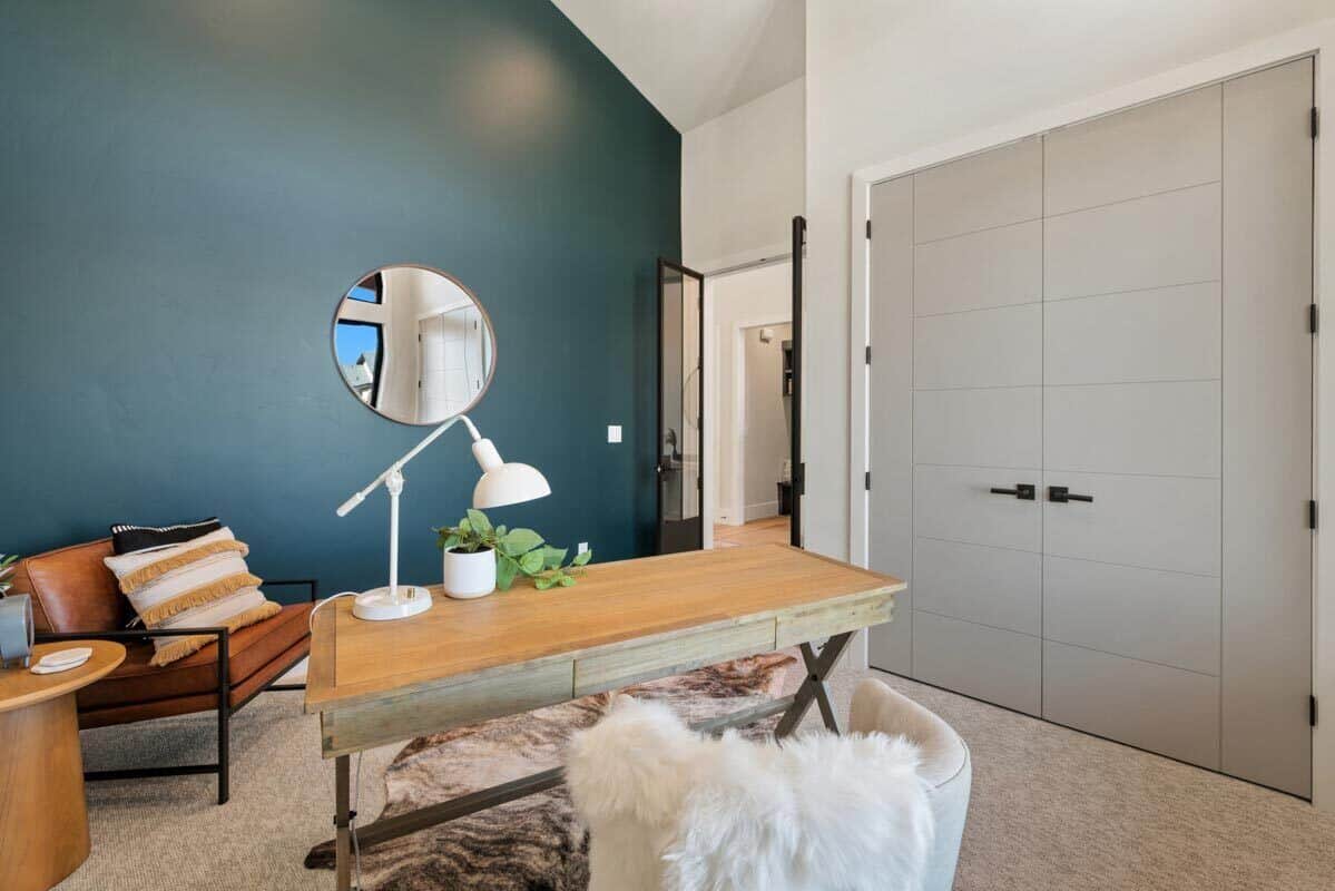 内政部暗蓝绿色口音墙,一个木制的桌子,和一个内置的壁橱里灰色的双扇门背后隐藏。