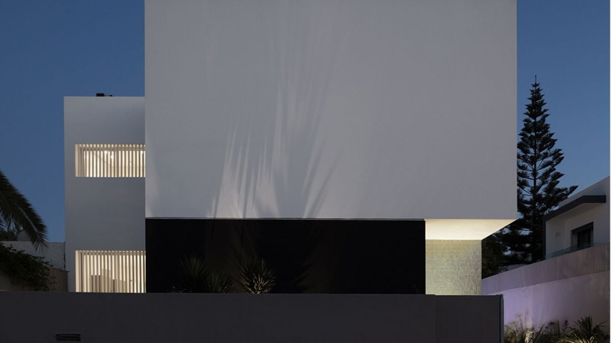 这张照片显示了在一个没有窗户的白色盒子形状结构之外,这是高墙上装饰着黑色和蓝色瓷砖。