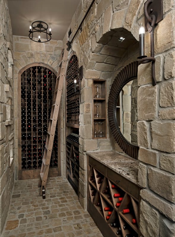 酒窖里有石墙、内置的酒架和一张顶部有一面圆形镜子的桌子。