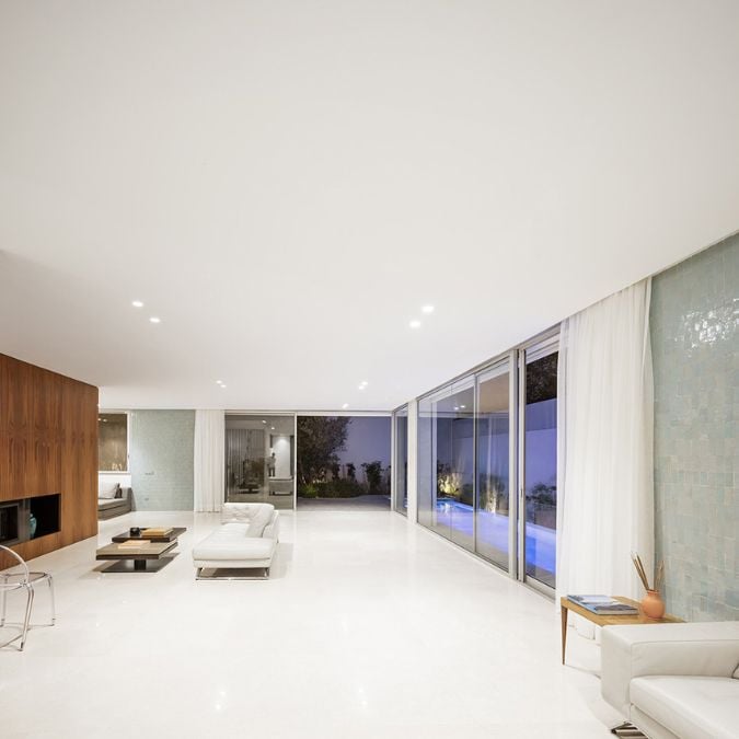 一个室内的照片与简约的家具布局宽敞的客厅。房间功能的墙的玻璃,它提供了一个清晰的外面的景色和允许大量的自然光线充斥空间。