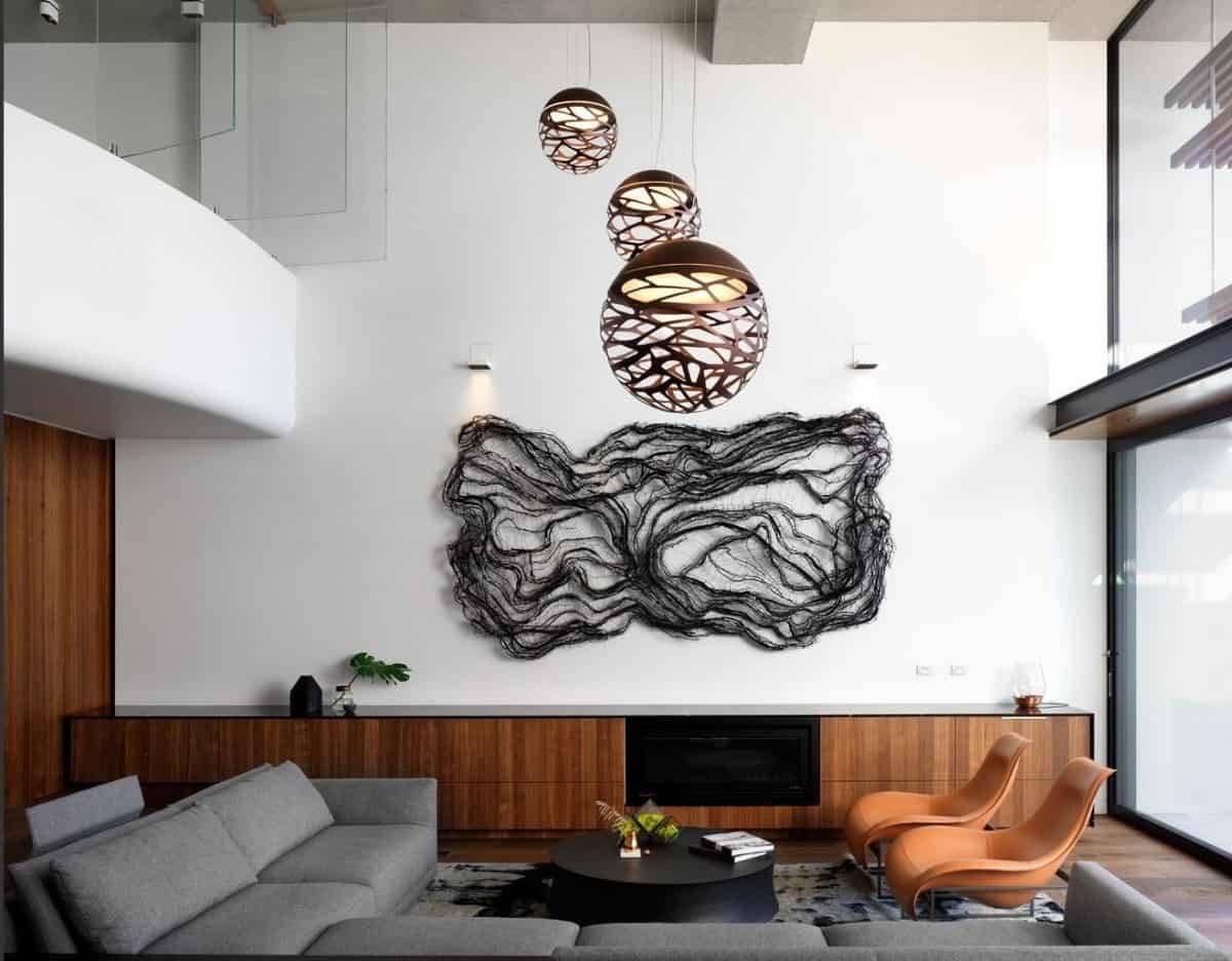 这个宽敞的客厅装饰着超大的球形挂件和固定在控制台桌子上方的当代墙壁艺术。