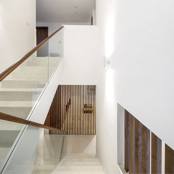 这张照片展示了一个u型的楼梯设计独特,结合了木栏杆和玻璃面板。