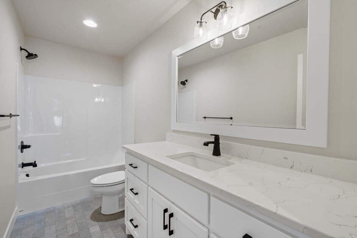 这个白色的浴室与锻铁装置和五金形成了美丽的对比。