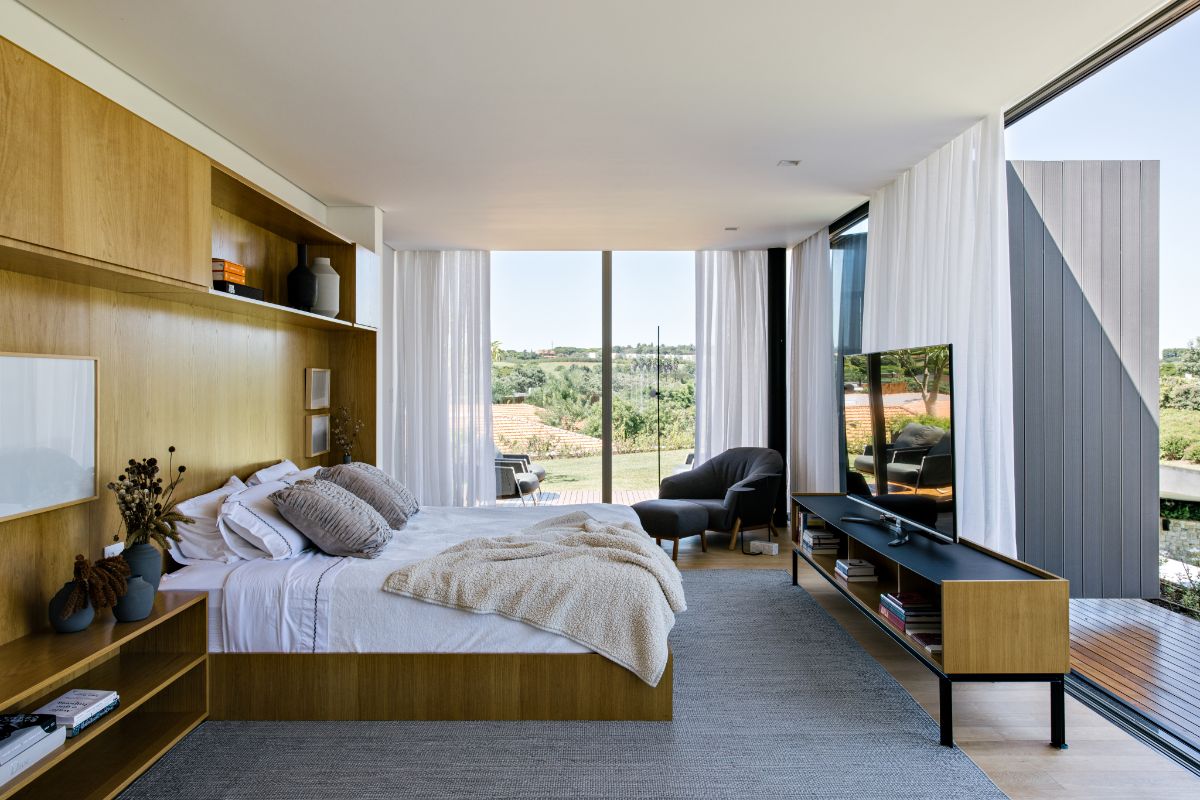 宽敞的卧室有一面落地玻璃墙，可以清楚地看到周围的景观。