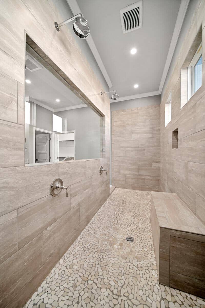 狭长的淋浴区有一张瓷砖长椅，铬固定装置和一扇全景窗。