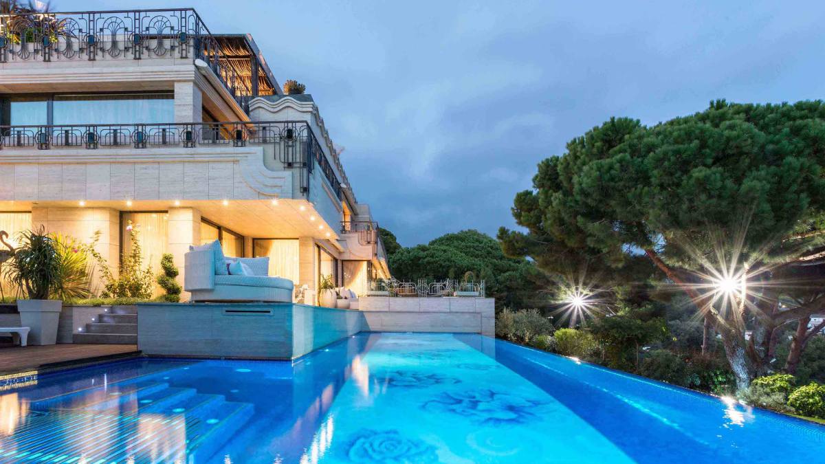 这张外部照片突出了游泳池美丽的蓝色水，以及照亮房子某些部分的令人愉快的灯光。
