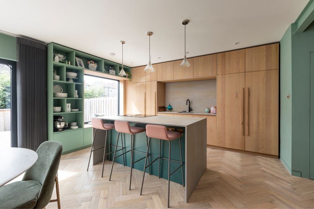 这是一个厨房区域的图像，展示了一个中央岛，配有椅子和橡木人字形地板设计，为厨房的整体美学增添了一丝优雅和精致。