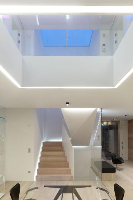 这室内照片强调上面的长方形的透明玻璃屋顶放置餐桌和楼梯。