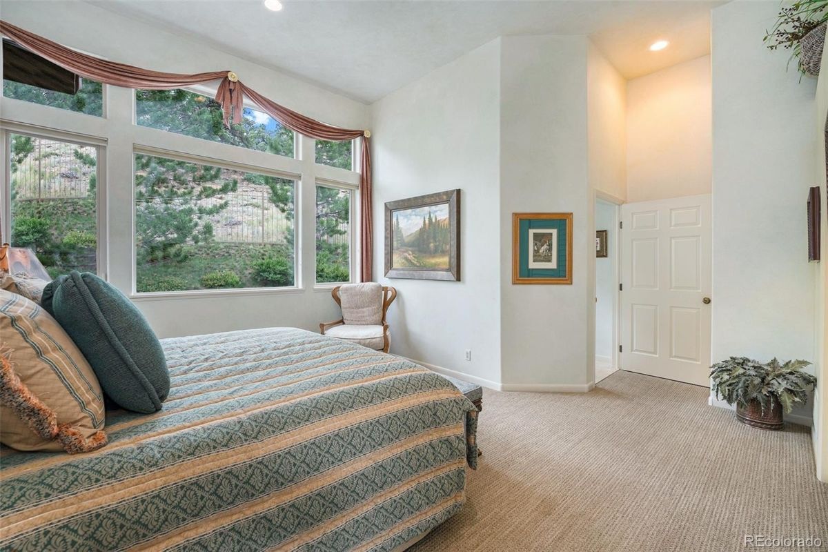 卧室有一个铺天盖地的地毯,一个舒适的床上,和玻璃窗,外面展示视图。