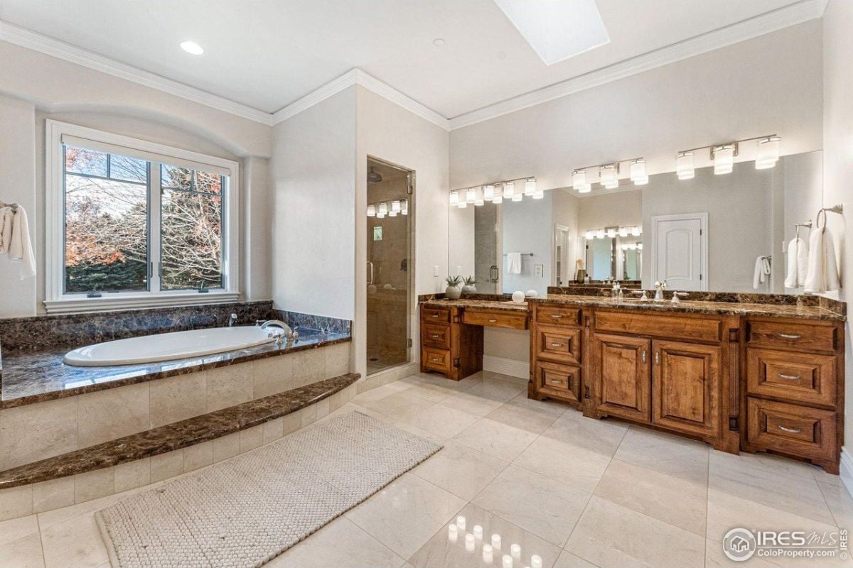 浴室有一个内置的浴缸和一个木制虚荣顶部有一个浴室的镜子和由优雅的墙灯点亮。