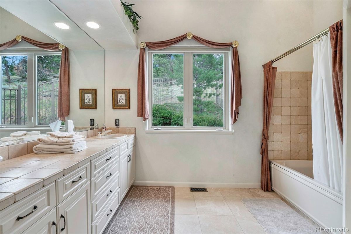 浴室有一个虚荣心瓷砖灶台和一个内置的浴缸与窗帘的隐私。