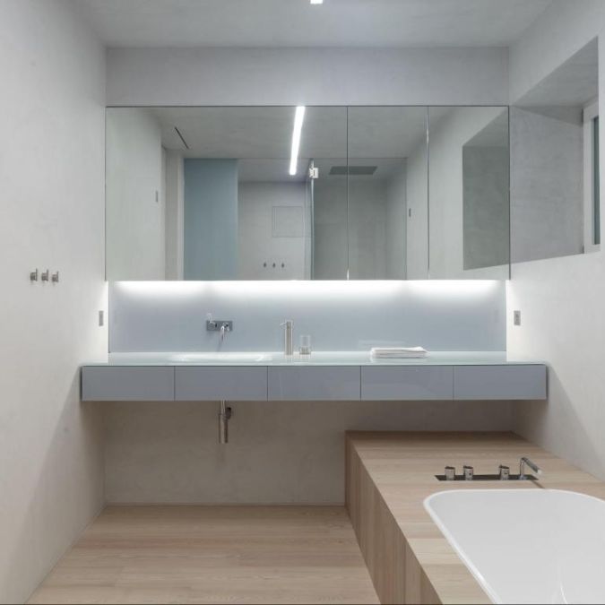 这室内照片凸显了浴室有一个盆地下沉,一个广泛的固定在墙上的镜子,和一个浴缸。