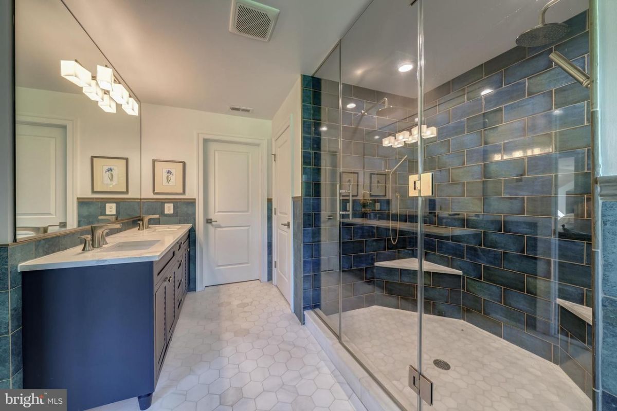 浴室设有一个带瓷砖台面的梳妆台和一间带玻璃外壳的淋浴间。