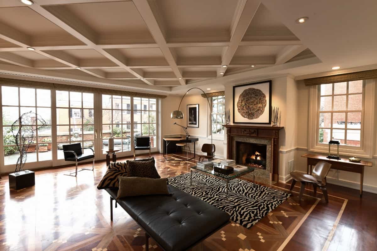 这间客厅设有格子天花板，一座舒适的壁炉，以及通往露台的超大滑动玻璃门。