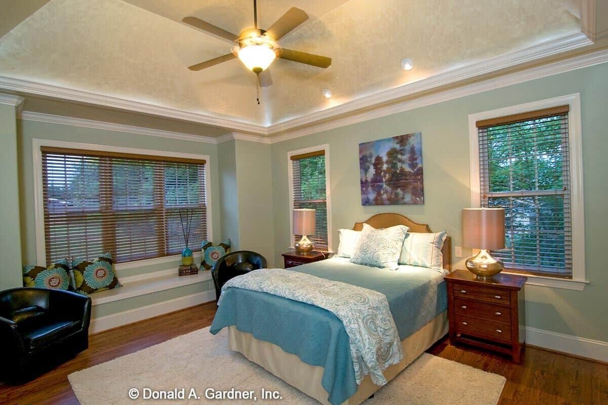 主卧室有一个托盘天花板和一个靠窗的座位强调色彩斑斓的枕头。