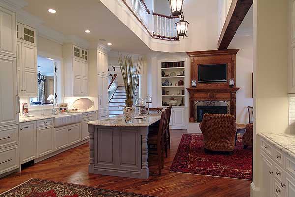 厨房里有白色的橱柜和灰色的岛，通往客厅