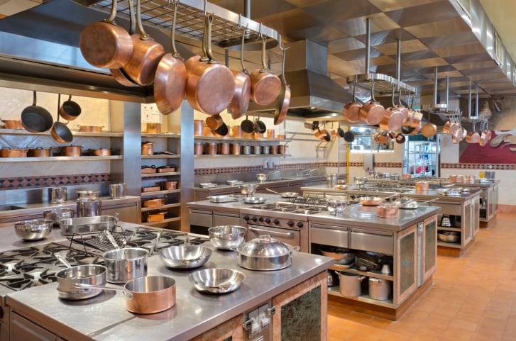 大型商业厨房，铜锅挂在一系列锅架上